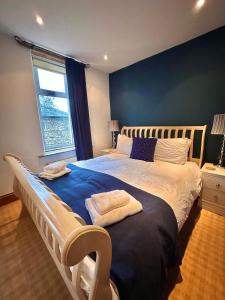 a bedroom with a large bed with a blue wall at Clare's Cottage Near Cartmel - Dog Friendly, Homely, Aga, Log Burners, Disney Plus & Netflix in Holker