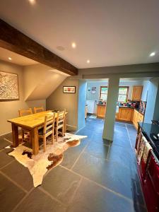 a dining room with a wooden table and a kitchen at Clare's Cottage Near Cartmel - Dog Friendly, Homely, Aga, Log Burners, Disney Plus & Netflix in Holker