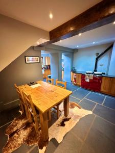 a dining room with a wooden table and a kitchen at Clare's Cottage Near Cartmel - Dog Friendly, Homely, Aga, Log Burners, Disney Plus & Netflix in Holker