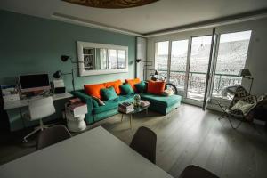uma sala de estar com um sofá verde com almofadas laranja em 16th District Spacious Sophistication em Montreuil