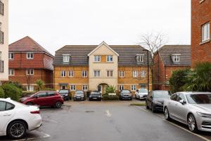 um parque de estacionamento com carros estacionados em frente a casas em The Morden Collection em Londres