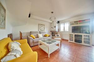 a living room with a yellow couch and a tv at Casa Margarita, al lado de Laredo in Rada