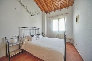 a bedroom with a bed with white sheets and a window at Casa Margarita, al lado de Laredo in Rada