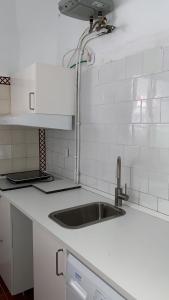 a kitchen with a sink and white tile walls at APCH5 Marga in Chinchón