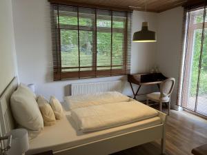 een slaapkamer met een bed, een bureau en ramen bij Ellernhof in Dahlenburg