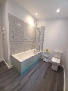 a bathroom with a bath tub and a toilet at Chapter Farm Cottages in Canterbury