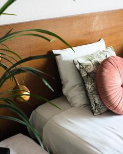 a bed with a wooden head board with pillows and a plant at Hotel 't Vertrek in Boxmeer