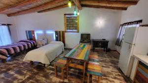 a room with two beds and a table and a refrigerator at La Posada del Rio in Tilcara