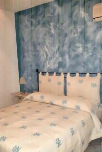 a bed with white sheets and blue flowers on it at Elegant House with Sea View in Cannigione in Cannigione