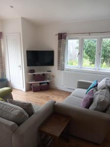 a living room with a couch and a flat screen tv at Chapter Farm Cottages in Canterbury