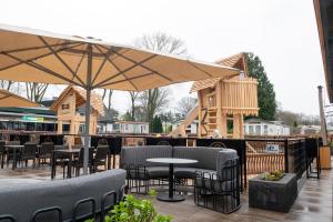 a patio with tables and chairs and an umbrella at Camping de Konijnenberg Tiny House in Harderwijk