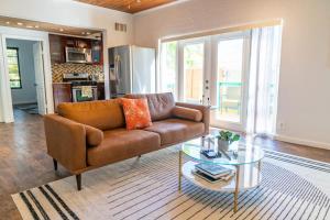 a living room with a brown couch and a glass table at Hidden Gem Off Atlantic Ave, Just Steps From Beach in Delray Beach