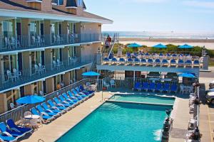 a hotel with a swimming pool and chairs and a beach at Fleur de Lis Beach Motel in Wildwood Crest