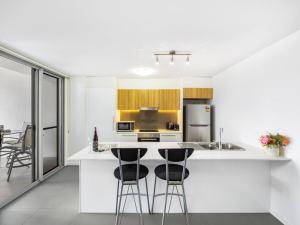 a kitchen with white countertops and black bar stools at Chic Modern Retreat 1BR Apt w pool Kelvin Grove in Brisbane