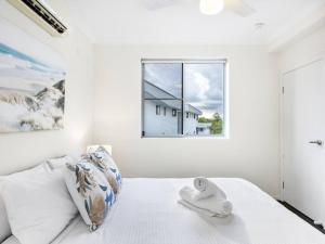 a white bedroom with a bed with a window at Chic Modern Retreat 1BR Apt w pool Kelvin Grove in Brisbane