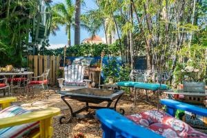 a patio with chairs and tables and palm trees at Hidden Gem Off Atlantic Ave, Just Steps From Beach in Delray Beach