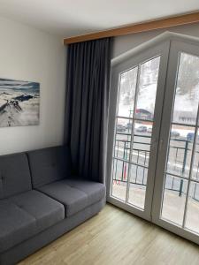 a living room with a couch and a large window at Hotel Grünwaldkopf in Obertauern