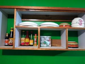- une étagère en bois avec des bouteilles et de la vaisselle dans l'établissement Ferafolia Highlands Home Stays, à Auki