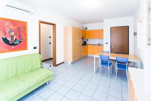 een woonkamer met een groene bank en een tafel bij Altanea Apartments con piscina in Caorle
