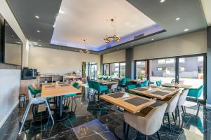 a restaurant with wooden tables and green chairs at MCity Hotel in Arad
