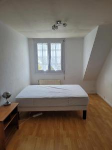 een witte slaapkamer met een bed en een raam bij Maison de 5 chambres avec jardin clos et wifi a Dammartin en Goele in Dammartin-en-Goële