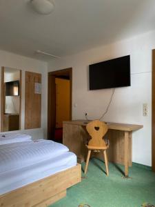 a bedroom with a bed and a desk and a television at Hotel Grünwaldkopf in Obertauern