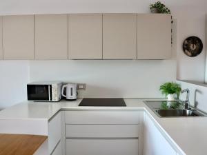 a white kitchen with a sink and a microwave at Portopiccolo Apartments - Loggia sul mare in Sistiana +20 photos