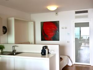 eine Küche mit einem Waschbecken und einem Gemälde an der Wand in der Unterkunft Portopiccolo Apartments - Loggia sul mare in Sistiana + 17 Fotos