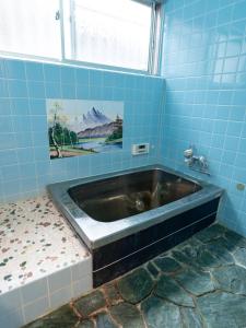 a bath tub in a blue tiled bathroom at HOSTEL KURIYA OSAKA in Izumi-Sano +43 photos