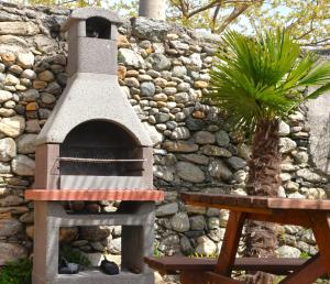 um forno de pizza sentado ao lado de uma parede de pedra em Camping Italia90 Caravan&Bungalow em Domaso