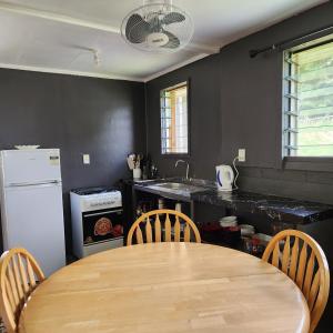 a kitchen with a wooden table and chairs and a refrigerator at Eua Accommodation in ‘Ohonua