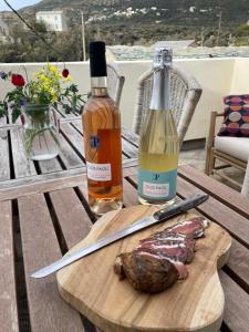 eine Flasche Wein und ein Steak auf einem Holztisch in der Unterkunft La Vue 360 in Centuri