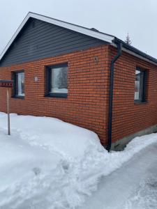 une maison en briques rouges avec de la neige devant elle dans l'établissement Eget hus i Vittjärv, à Boden