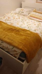 ein Bett mit einer gelben Decke darüber in der Unterkunft Bel appartement 4 personnes in Port-en-Bessin-Huppain