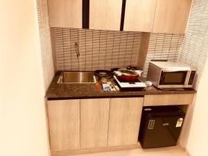 a small kitchen with a sink and a microwave at The Lodgers 2 BHK Serviced Apartment Near Artemis Hospital Sector 57 Gurgaon - Nearest Metro Station Sector 54 Chowk in Gurgaon