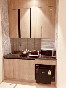 a kitchen with a microwave and a stove top oven at The Lodgers 2 BHK Serviced Apartment Near Artemis Hospital Sector 57 Gurgaon - Nearest Metro Station Sector 54 Chowk in Gurgaon