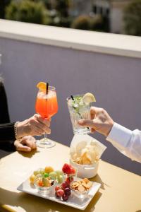 two people holding cocktails and a plate of food on a table at Maritan Hotel & Spa in Padova