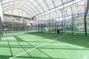 a tennis court inside of a building with a glass ceiling at Aparthotel AnyosPark Mountain & Wellness Resort in Anyós
