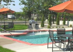 a pool with chairs and tables and an umbrella at STUNNING Architect loft by CozySuites in Saint Louis