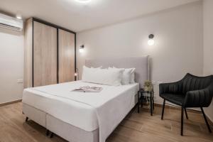 um quarto com uma cama branca e uma cadeira preta em jacuzzi apartment em Jerusalém