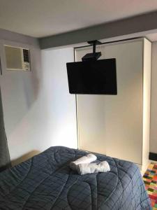 a bedroom with a bed with a tv on the wall at Studio no Jabaquara a 2,8km da Expo imigrantes in Sao Paulo