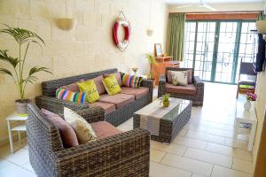 a living room with wicker couches and a table at Casa Sammy in Sannat