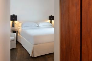 a bedroom with a bed with white sheets and pillows at Le Metropolitan, Paris Tour Eiffel, a Tribute Portfolio Hotel in Paris