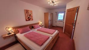 1 Schlafzimmer mit 2 Betten mit roten Kissen und einem Fenster in der Unterkunft Georgihof Ferienwohnungen in Murnau am Staffelsee
