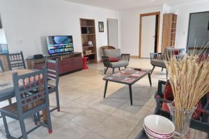 ein Wohnzimmer mit Stühlen, einem Tisch und einem TV in der Unterkunft Chez la Mouzotte 