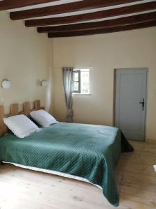 1 dormitorio con 1 cama grande con manta verde en Maison atypique semi-troglodyte, en Chinon