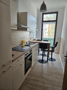 cocina con armarios blancos, mesa y comedor en Westend 2, en Plauen