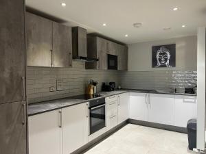 una cocina con armarios blancos y una pintura en la pared en Cosy Suite in Shirley, en Solihull
