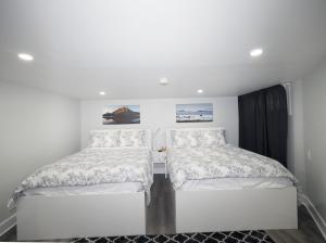 two beds in a room with white walls at Serene Niagara Guest House in Niagara Falls