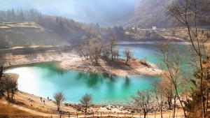 una gran piscina de agua azul a un lado de una montaña en Tenno Lake Sun en Tenno